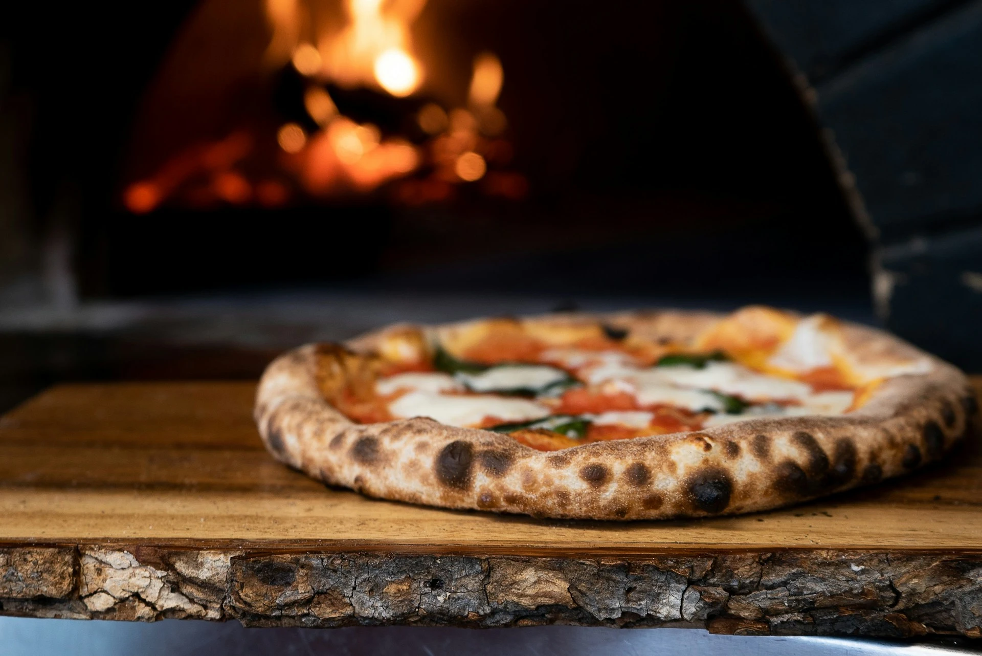 A freshly baked pizza on a plate, ready to eat, with a warm fire burning in the background, creating a cozy atmosphere.